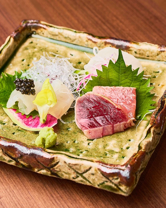土の風合いの器に盛られた鮮魚の刺身とキャビアの盛り合わせ